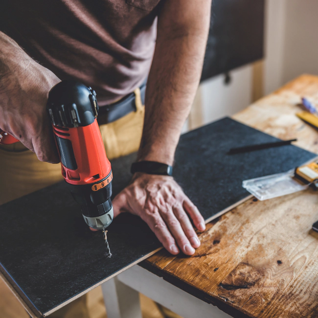 handyman working on a plank of black colored wood